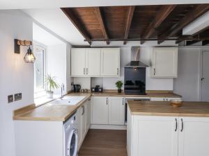 a kitchen with white cabinets and wooden ceilings at Hemdin Cottage in Pickering +26 photos
