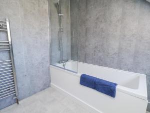 a bathroom with a white bath tub with a blue towel at Hemdin Cottage in Pickering