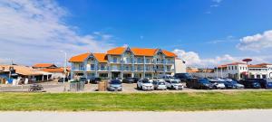 a large building with cars parked in a parking lot at Brise Marine, piscine, confort entre dune et océan in Biscarrosse