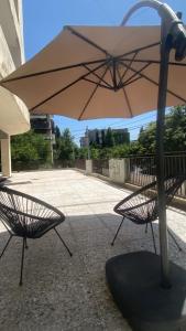 ein Sonnenschirm und zwei Stühle auf einem Bürgersteig in der Unterkunft Lomi's Homey - Rooms in Tbilisi City