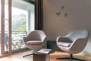 two chairs and a table in a room with a window at Havila Hotel Geiranger in Geiranger
