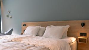a bedroom with a bed with white sheets and pillows at Havila Hotel Geiranger in Geiranger