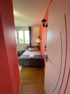 Cette petite chambre comprend un lit et un mur rouge. dans l'établissement Chambres avec espaces communs équipés parfait pour séjour professionnel ou ambiance conviviale, à Laval