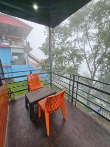 un balcon avec deux chaises et une table sur un balcon dans l'établissement Green Valley Cottage, à Dhanaulti