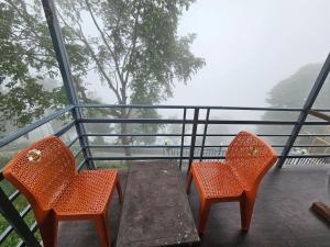 deux chaises orange et une table en bois sur un balcon dans l'établissement Green Valley Cottage, à Dhanaulti