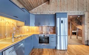 a kitchen with blue cabinets and a stainless steel refrigerator at Gaustatoppen Hytteutleie in Gaustablikk