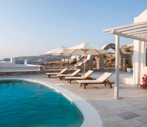 basen z leżakami i parasolami obok domu w obiekcie Thalia Luxe 4-Bedroom Pool Villa w mieście Mykonos