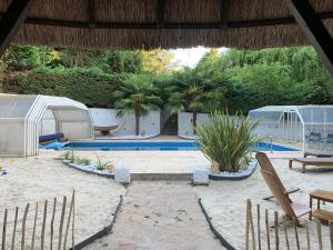 a patio with a pool and tents and palm trees at La Chaumière Luxury Domain with 2 Apartments Spa and Pool near Disneyland in Coupvray