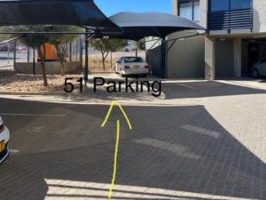 a parking lot with a car parked under an umbrella at Wild Olive at 51 in Windhoek