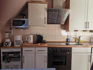 a kitchen with white cabinets and a stove top oven at Ferienwohnung-mit-Balkon in Pinnow +4 photos