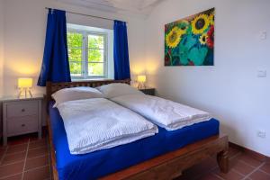 ハーフクルークにあるLandhaus-Marwede App7の青いシーツのベッドと窓のある寝室