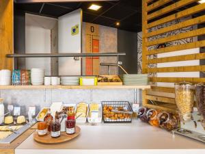a kitchen with a counter with bread and other foods at ibis budget Angoulême Centre in Angoulême