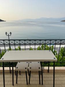 a white table and bench on a balcony overlooking the water at Studios on the beach in Galaxidi