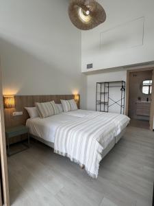 a bedroom with a large white bed and a ceiling at Apartamentos El Puerto Ayamonte in Ayamonte