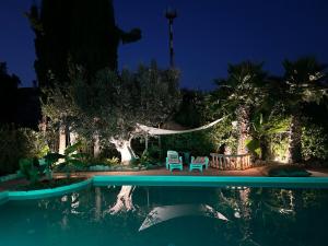 a swimming pool at night with two chairs and a hammock at Cottage Milvia piscina privata rifugio romantico vicino al mare in Tortoreto Lido +8 photos