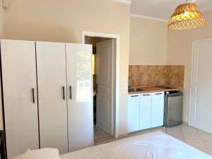 a kitchen with white cabinets and a chandelier at Komi's Pink Paradise 1 in Kómi +15 photos