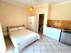 a bedroom with a white bed and a kitchen at Komi's Pink Paradise 1 in Kómi