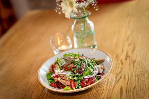 a bowl of salad on a wooden table with a vase at Castle Arch Hotel in Trim
