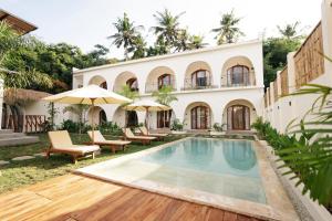 a villa with a swimming pool and a house at TWINFIN Surf House in Kuta Lombok