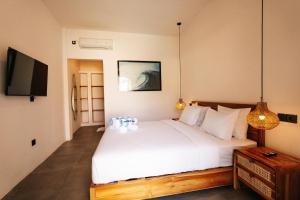 a bedroom with a white bed and a tv at TWINFIN Surf House in Kuta Lombok
