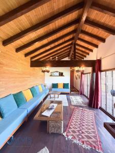 a living room with a blue couch and a table at Domaine Essanya Chalet and bungalows Nature quiet and private pool in Dawwār al Frinine