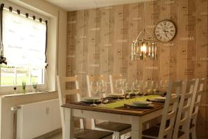 a dining room table with chairs and a clock on the wall at Wellness-Ferienwohnung-EifelErnstbergblick 1 in Daun +16 photos