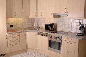 a kitchen with white cabinets and a sink and a stove at Wellness-Ferienwohnung-EifelErnstbergblick 1 in Daun