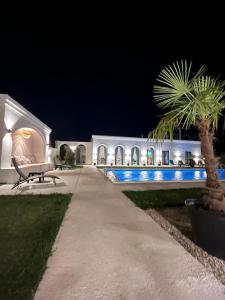 a pathway in front of a white building with a palm tree at Villa Gyos in Costinesti