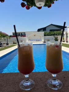two drinks sitting on a table next to a swimming pool at Villa Gyos in Costinesti