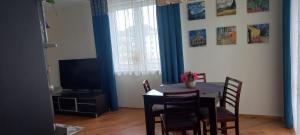 a dining room with a table and chairs and a television at Apartament Na Wydmie in Ustka +1 photo