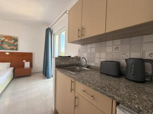 a kitchen with a sink and a bed in a room at Elga Hotel & apartments in Kardamaina