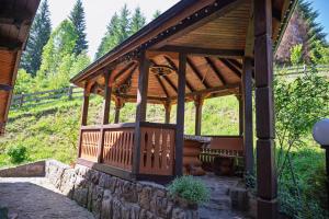 a wooden gazebo in a field with trees at Апартаменти у Яни in Yablunytsya