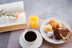 a plate of food and a cup of coffee and a book at Limnos View Apartments in Agios Ioannis Kaspaka