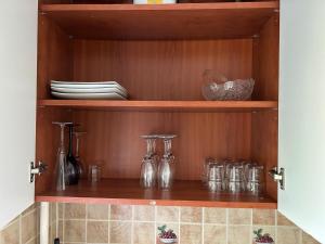 a wooden cabinet with glasses and plates on it at Danės 5 apartament in Klaipėda