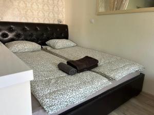 a bed with a black headboard and a bag on it at Danės 5 apartament in Klaipėda