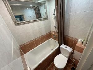 a bathroom with a tub and a toilet and a mirror at Danės 5 apartament in Klaipėda +8 photos