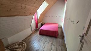 a small bedroom with a pink bed in a attic at Maison 10 personnes Chez Perrine et Nicolas in La Bourboule
