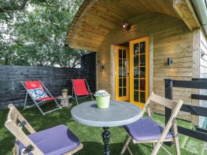 a patio with chairs and a table in front of a cabin at Under the Oak Tree Shepherd's Hut in Bristol +10 photos