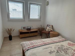 a bedroom with a bed and a desk and two windows at Kalina in Bigovo
