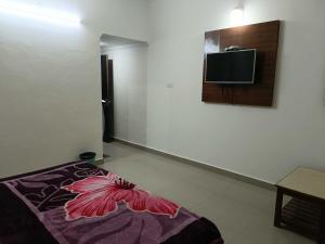 a room with a bed and a tv on a wall at Collection O Shri Mata Vaishno Devi Railway Junction Formerly Sai Mahal in Katra