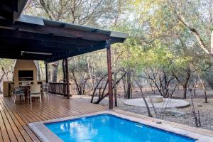 a wooden deck with a swimming pool and a table at Gemsbok Place in Marloth Park