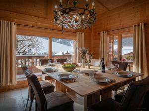 a dining room with a large wooden table with chairs at Chalet Le San Marco - OVO Network in La Clusaz
