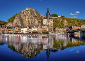 une ville sur l'eau avec un pont et une montagne dans l'établissement Hôtel de la Poste, à Gedinne