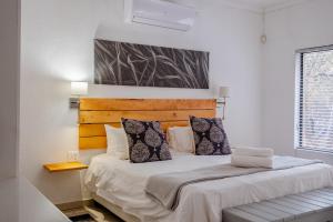 a bedroom with a large bed with white sheets and pillows at Gemsbok Place in Marloth Park