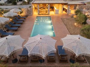 an outdoor pool with chairs and umbrellas next to a pool at ROOTS Nature Living Milos in Adamantas