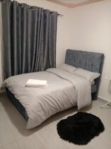 a bed with a blue headboard and a black curtain at Luqman Apartments in Meru