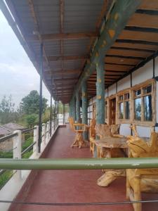 a porch of a building with wooden tables and chairs at Fountain Brook Gardens & Resort in Thika
