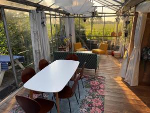 a room with a white table and chairs in a greenhouse at Vrijstaande accommodatie Glamping de Kas InN in Hank