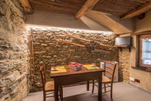 a table and chairs in a room with a stone wall at La Mason dla Grà in Frassinetto