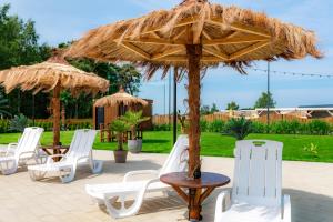 a table and chairs under a straw umbrella at Domki Piaskowa11 Palm Resort & Wellness - Basen, Jacuzzi, Balia, Sauna, Egzotyczne Papugi Ara in Łeba +73 photos